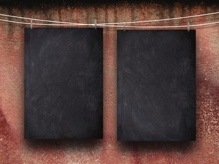 Close-up of two blank blackboard frames hanged by pegs against red weathered wall background