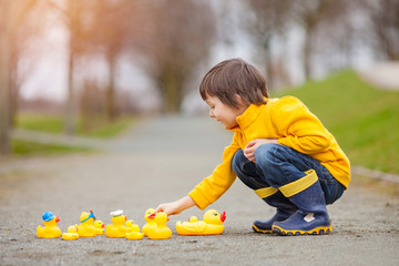 Poster - Adorable child, boy, playing in park with rubber ducks, having f