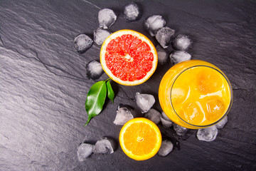 Wall Mural - Fresh orange juice with ice on dark stone background