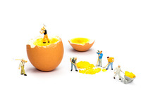 Team Of Miniature Human Figurines Transporting Chicken Egg Yolk
