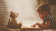 © JenkoAtaman - child little girl reading a magic book in dark home