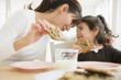 © JGI/Jamie Grill/Blend Images - Hispanic mother and daughter eating together