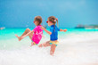 © travnikovstudio - Little girls having fun at tropical beach during summer vacation playing together at shallow water