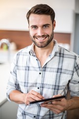 Wall Mural - Happy young man using digital tablet in kitchen