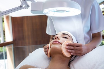 Wall Mural - Masseuse cleaning woman face with cotton swabs