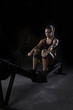 © RooM The Agency - Moody shot of a strong young woman in sportswear using a rowing machine in the gym