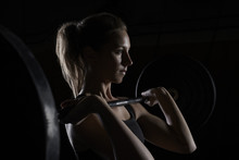 Young Woman Lifting Barbell In Gym