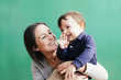 © Westend61 - Portrait of happy mother with her little son in front of green background