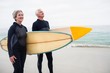 © Wavebreak Media - Senior couple with surfboard standing on the beach