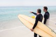 © Wavebreak Media - Father and son with surfboard pointing at a distance