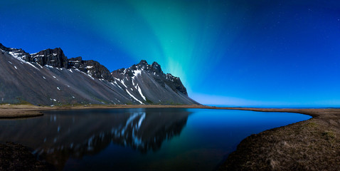 Wall Mural - panoramic of northern lights and mountains behind a lake