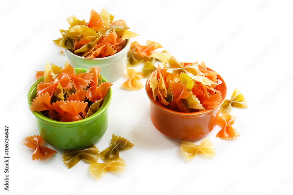 Colorful bow pasta in bowls on white background, close up