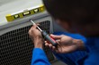© Wavebreak Media - Handyman testing air conditioner with screwdriver