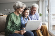 © Westend61 - Grandparents and their granddaughter sitting together on the couch looking at digital tablet