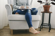 © Westend61 - Woman sitting in armchair writing on notepad