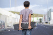 © Westend61 - Spain, Tenerife, back view of boy holding his skateboard behind his back