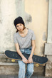© Westend61 - Portrait of young female skate boarder with her skateboard in front of a facade