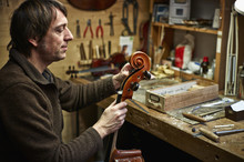 Violin Maker In His Workshop Adjusting A Cello Mechanism