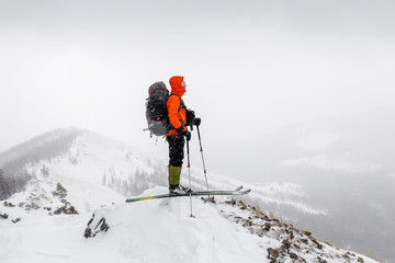 Man with skis and backpack standing on a mountain top