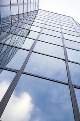 Wall Mural - modern glass building with reflections of blue sky and clouds