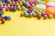 Candies colorful mix on yellow bright background with copy space