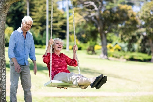 Senior Man Pushing His Partner On Swing Kaufen Sie Dieses