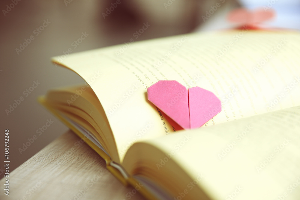 Book and heart shaped bookmark on a wooden table