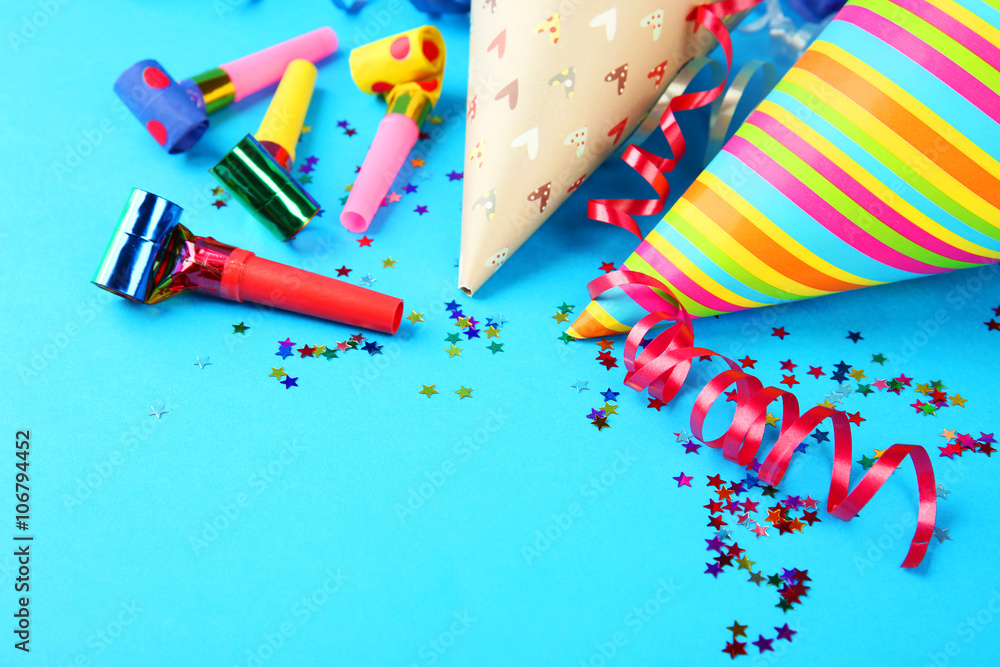 Birthday hats with serpentine streamer and noise makers on blue background