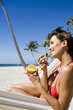 © plprod - femme à la plage dans un hamac mangeant un fruit