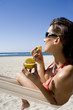 © plprod - femme à la plage dans un hamac mangeant un fruit