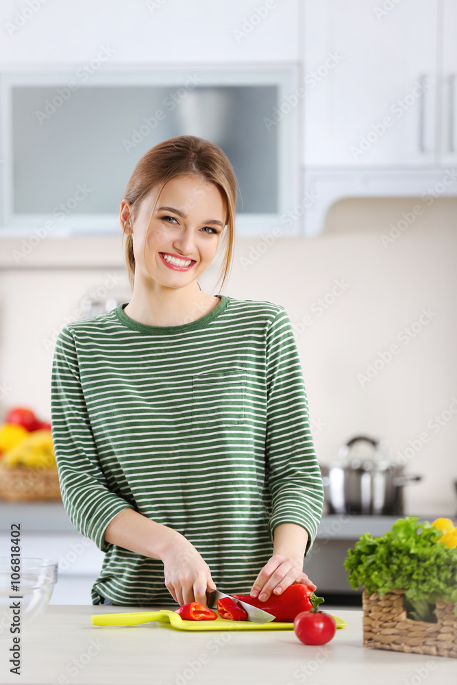 Young woman cutting vegetables for salad in the kitchen