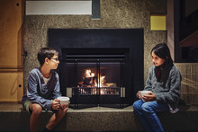 Mixed Race Children Having Hot Drink Together Near Fireplace