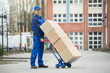 © Andrey Popov - Deliveryman Holding Trolley Loaded With Cardboard Boxes