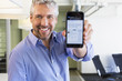 © Don Mason/Blend Images - Caucasian businessman holding cell phone in office