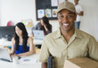 © JGI/Jamie Grill/Blend Images - Delivery man smiling in office