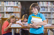 © Marc Romanelli/Blend Images - Student carrying stack of books in library
