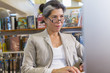 © Marc Romanelli/Blend Images - Older Hispanic woman using computer in library