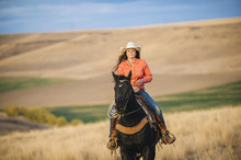 Caucasian Woman Riding Horse In Grassy Field