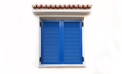 Window with closed blue shutters on white wall