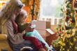 © Marc Romanelli/Blend Images - Caucasian grandmother and grandson opening presents near Christmas tree