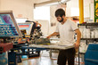 © Connect Images - Worker pressing ink on frame in screen printing workshop