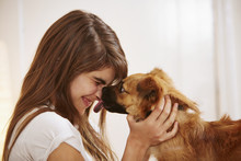 Young Woman Having Face Licked By Pet Dog