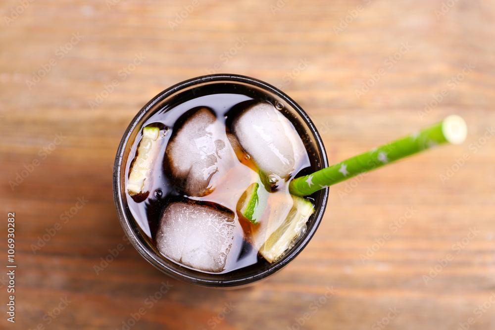 Cocktail with lime slices and ice blocks on wooden table, close up