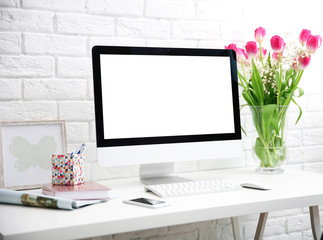 Stylish workplace with computer and tulips at home