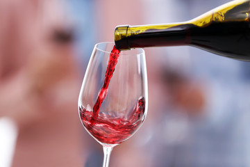 Wall Mural - Pouring red wine from bottle into glass, close up