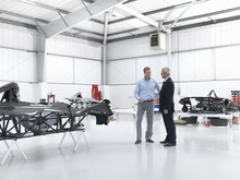 Salesman Discussing Supercar With Customer In Factory
