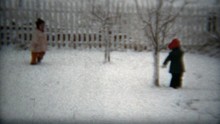 1960: Kids Leaving Fresh Tracks In Winter Snow In White Fenced Backyard.