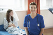 © Connect Images - Nurse sitting on end of patient's bed
