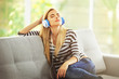 © Africa Studio - Relaxed young woman enjoying music with headphones on sofa, leisure and stress relief at home