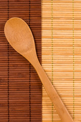 wooden spoon lying on a diagonal on two mats made of bamboo